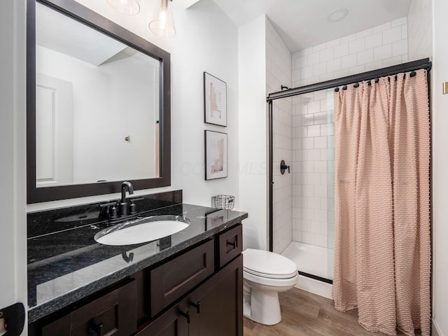bathroom featuring toilet, a shower stall, wood finished floors, and vanity