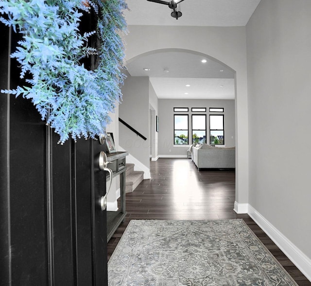 entryway featuring stairway, baseboards, dark wood-type flooring, arched walkways, and recessed lighting