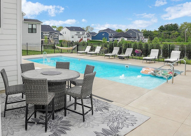 community pool with a patio area, a residential view, and fence