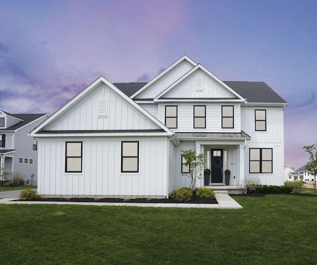 modern farmhouse style home featuring metal roof, board and batten siding, a front yard, roof with shingles, and a standing seam roof
