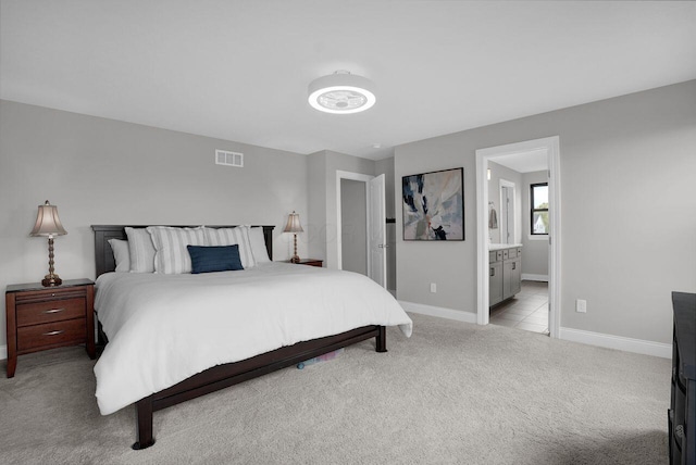carpeted bedroom with ensuite bath, baseboards, and visible vents