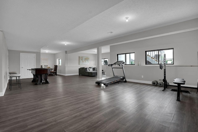 workout area with baseboards, dark wood finished floors, and a textured ceiling