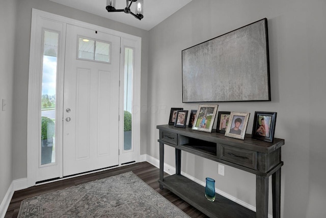entryway featuring a chandelier, baseboards, and dark wood-style floors