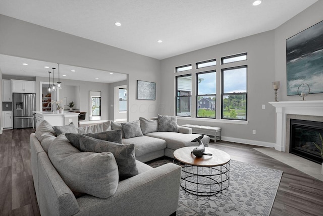 living area featuring baseboards, dark wood-style flooring, a fireplace, and recessed lighting