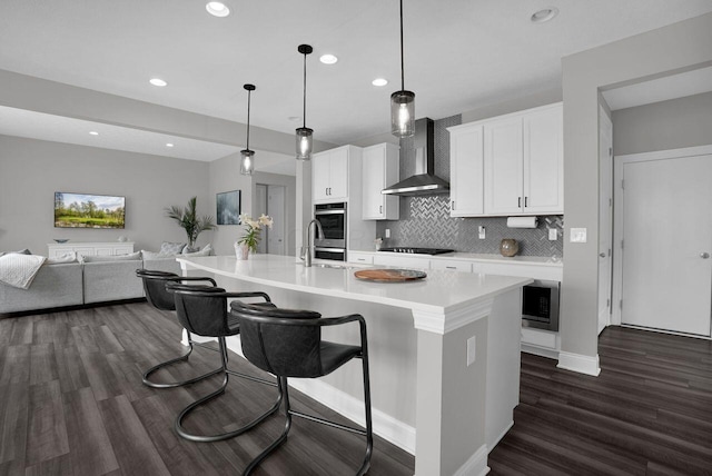 kitchen featuring dark wood-type flooring, recessed lighting, wall chimney exhaust hood, decorative backsplash, and appliances with stainless steel finishes
