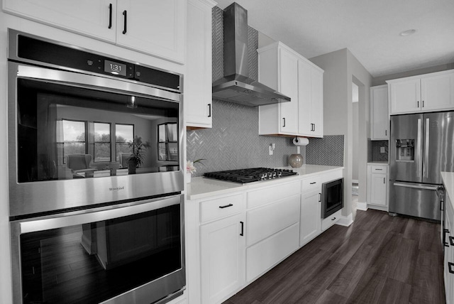 kitchen featuring wall chimney exhaust hood, stainless steel appliances, white cabinets, backsplash, and light countertops