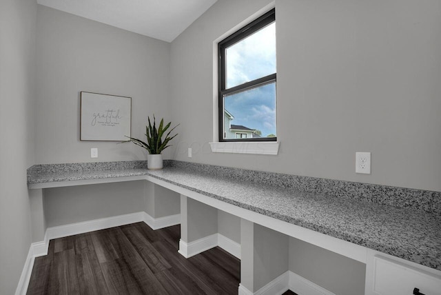 unfurnished office featuring baseboards, built in study area, and dark wood-type flooring
