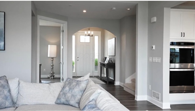 living area featuring visible vents, recessed lighting, dark wood finished floors, arched walkways, and baseboards