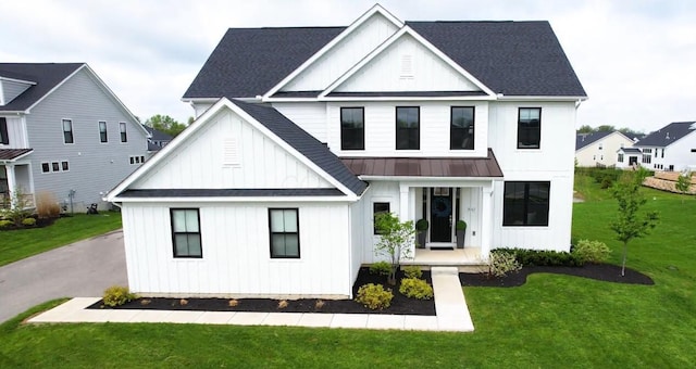 view of front of house featuring board and batten siding, a standing seam roof, a shingled roof, and a front lawn