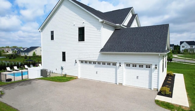 view of property exterior with cooling unit, fence, roof with shingles, driveway, and a fenced in pool