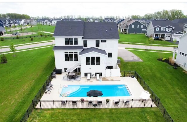 back of property featuring a lawn, a patio, a residential view, and a fenced backyard