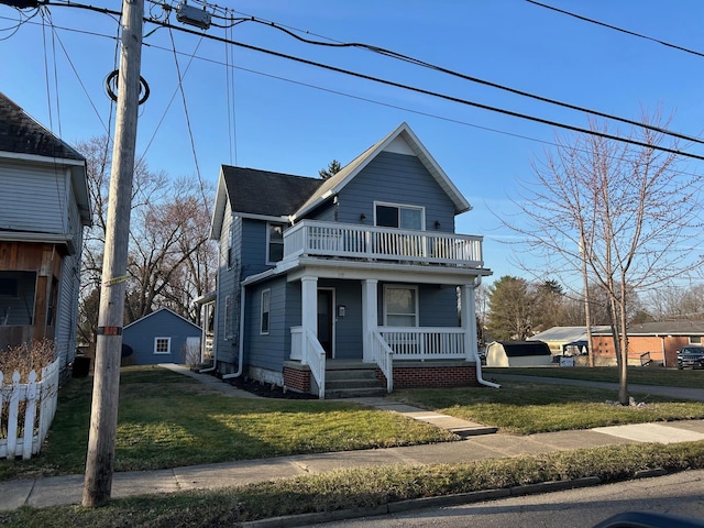 view of front facade with a balcony, a front lawn, and covered porch
