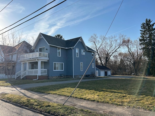 view of side of home with a yard, a porch, a garage, an outdoor structure, and a balcony