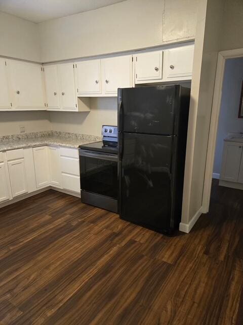 kitchen featuring white cabinetry, freestanding refrigerator, and electric range