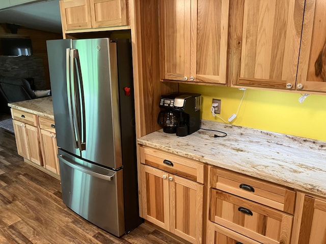 kitchen with dark wood-type flooring, freestanding refrigerator, and light stone countertops