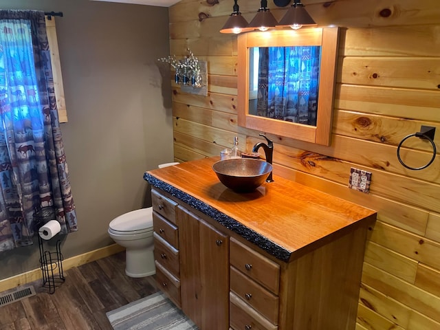 bathroom featuring toilet, baseboards, visible vents, wood finished floors, and vanity