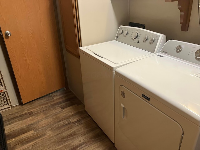 clothes washing area featuring washing machine and clothes dryer, laundry area, and dark wood-style flooring
