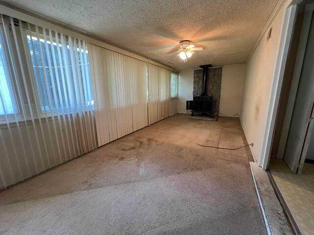 1054 S Hampton Rd, Columbus, OH 43227 - unfurnished living room featuring visible vents, a wood stove, a ceiling fan, a textured ceiling, and carpet flooring