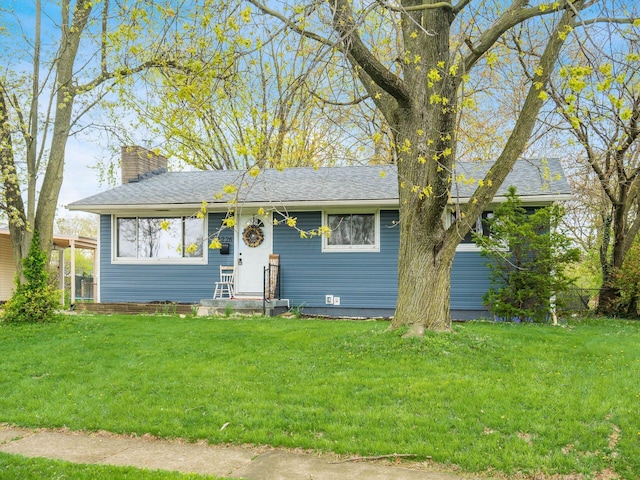 view of front of property featuring roof with shingles, a chimney, and a front lawn