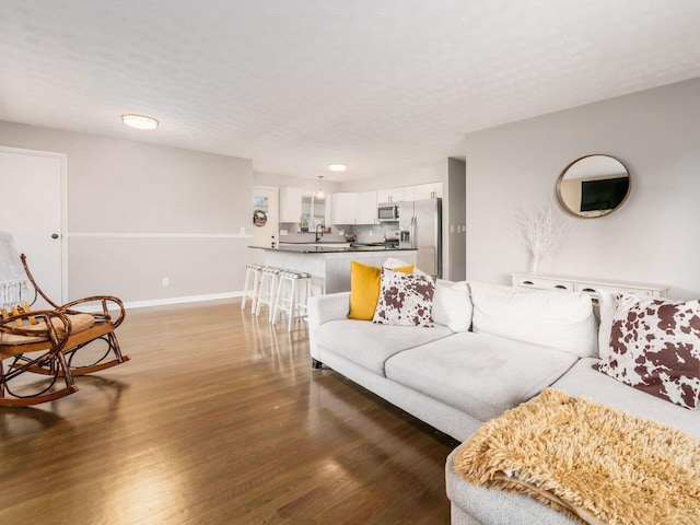 living area featuring light wood-type flooring, baseboards, and a textured ceiling