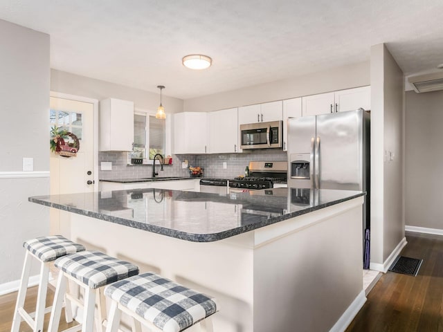 kitchen with baseboards, dark wood-style floors, backsplash, visible vents, and stainless steel appliances