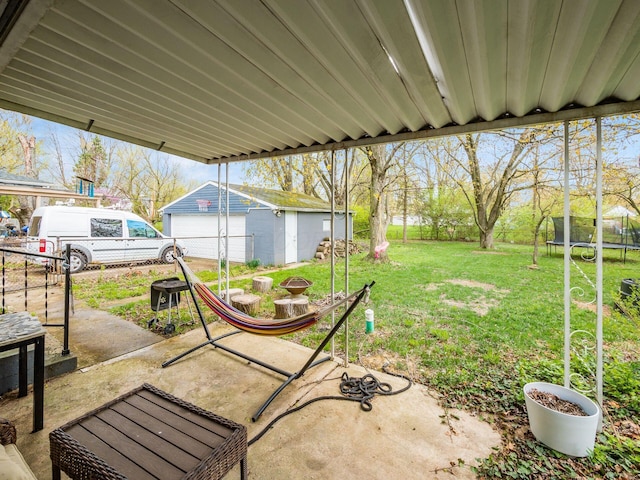 view of patio featuring a trampoline, a garage, fence, and an outdoor structure