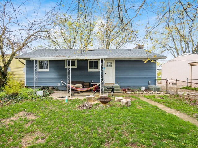 rear view of house with entry steps, an outdoor fire pit, a lawn, fence, and a gate
