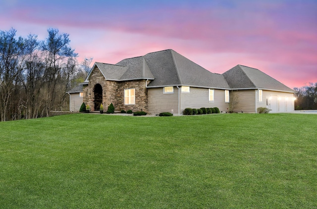 french provincial home featuring roof with shingles, a garage, concrete driveway, and a front lawn