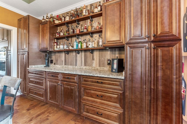 bar with dark wood-type flooring, a dry bar, and crown molding