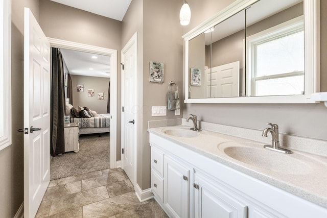 ensuite bathroom featuring double vanity, ensuite bathroom, baseboards, and a sink