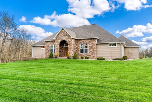 view of front of house with a front yard, stone siding, and a shingled roof