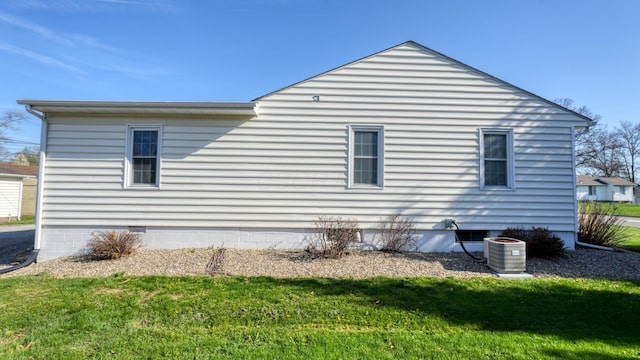 view of side of property with central AC, a lawn, and crawl space