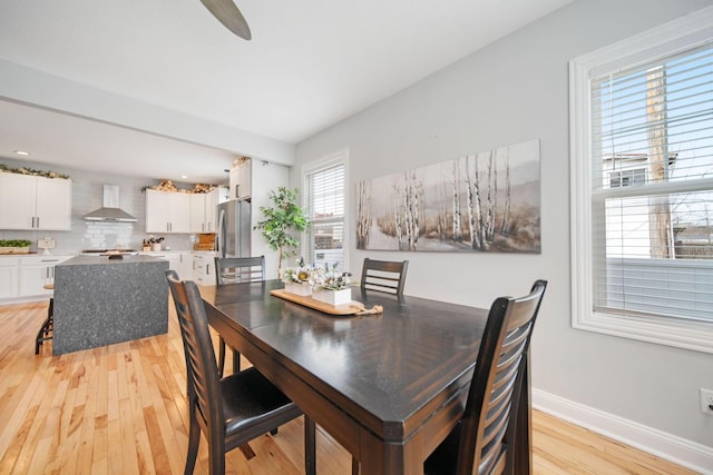 dining space with light wood-type flooring and baseboards