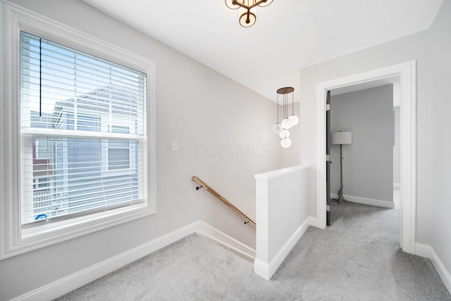 hall featuring carpet floors, an upstairs landing, and baseboards