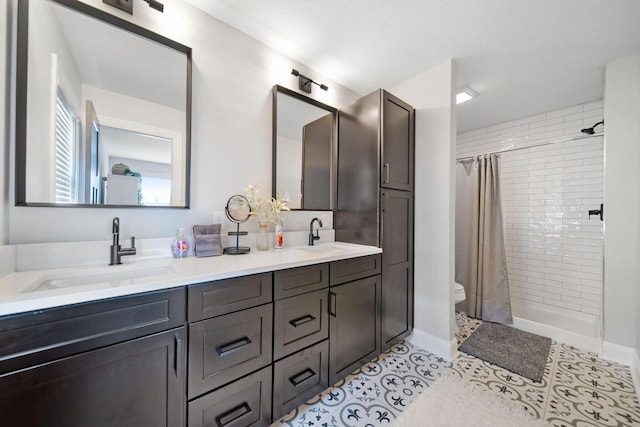 bathroom with toilet, a sink, double vanity, and tiled shower