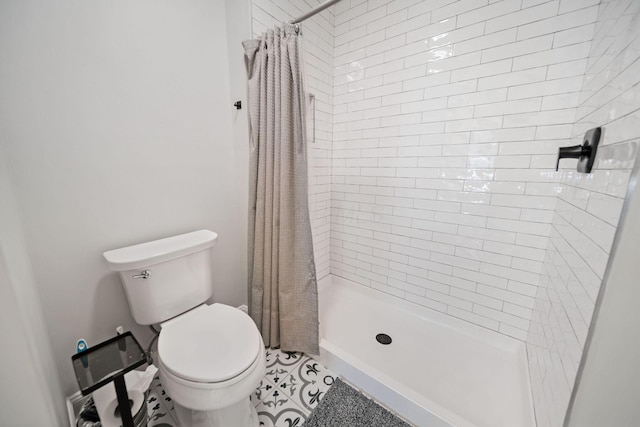 bathroom featuring toilet, tile patterned flooring, and a stall shower