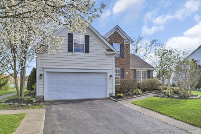 traditional-style home featuring a garage, aphalt driveway, and a front lawn