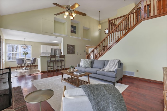living area featuring visible vents, ceiling fan with notable chandelier, wood finished floors, and stairs