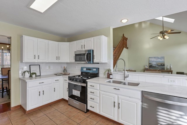 kitchen featuring white cabinets, a sink, appliances with stainless steel finishes, backsplash, and light tile patterned flooring