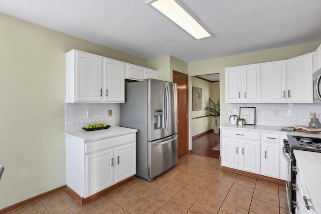kitchen featuring stainless steel appliances, light tile patterned floors, light countertops, and white cabinetry