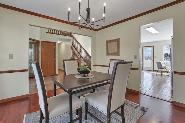 dining area with a notable chandelier, baseboards, crown molding, and wood finished floors