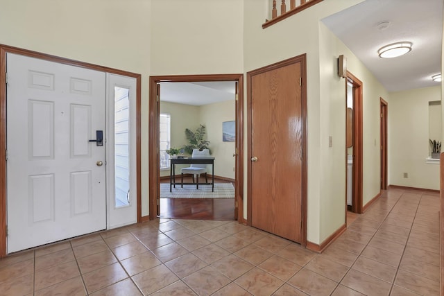 foyer entrance with light tile patterned floors and baseboards