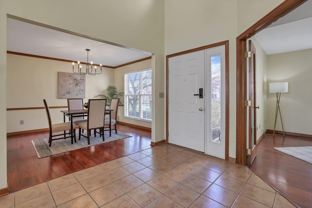 entryway with ornamental molding, baseboards, an inviting chandelier, and wood finished floors