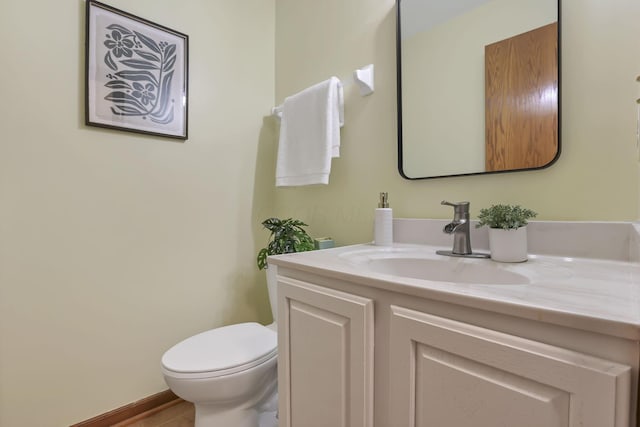 bathroom featuring toilet, vanity, and baseboards