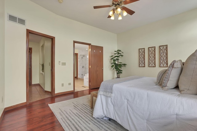 bedroom featuring ceiling fan, ensuite bath, visible vents, baseboards, and dark wood-style floors