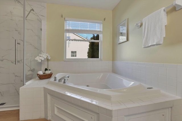 bathroom featuring a jetted tub and a marble finish shower