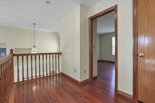 hallway with dark wood-type flooring and baseboards