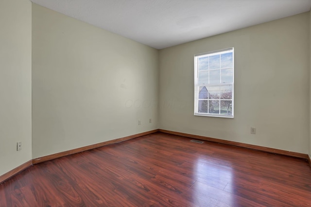 spare room with visible vents, baseboards, and wood finished floors