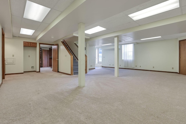 basement with baseboards, a paneled ceiling, light carpet, and stairs