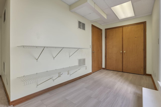 unfurnished bedroom with a closet, visible vents, a drop ceiling, and baseboards